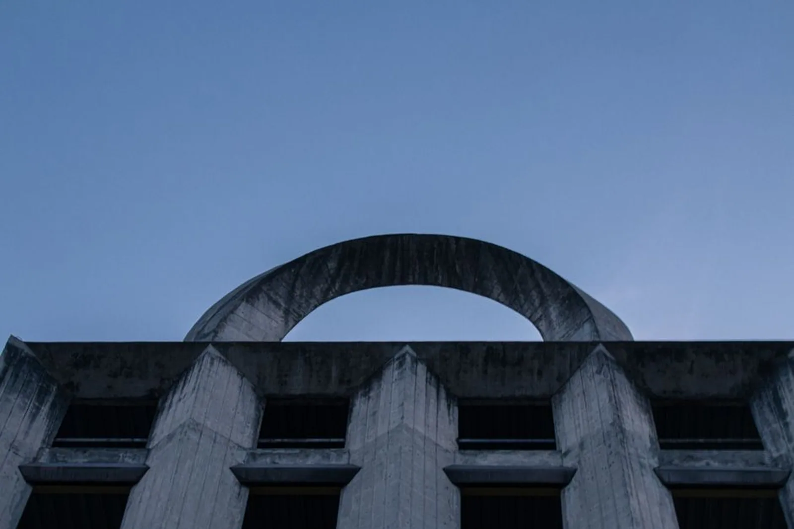 Arco de concreto de arquitetura modernista recortado contra o céu azul
