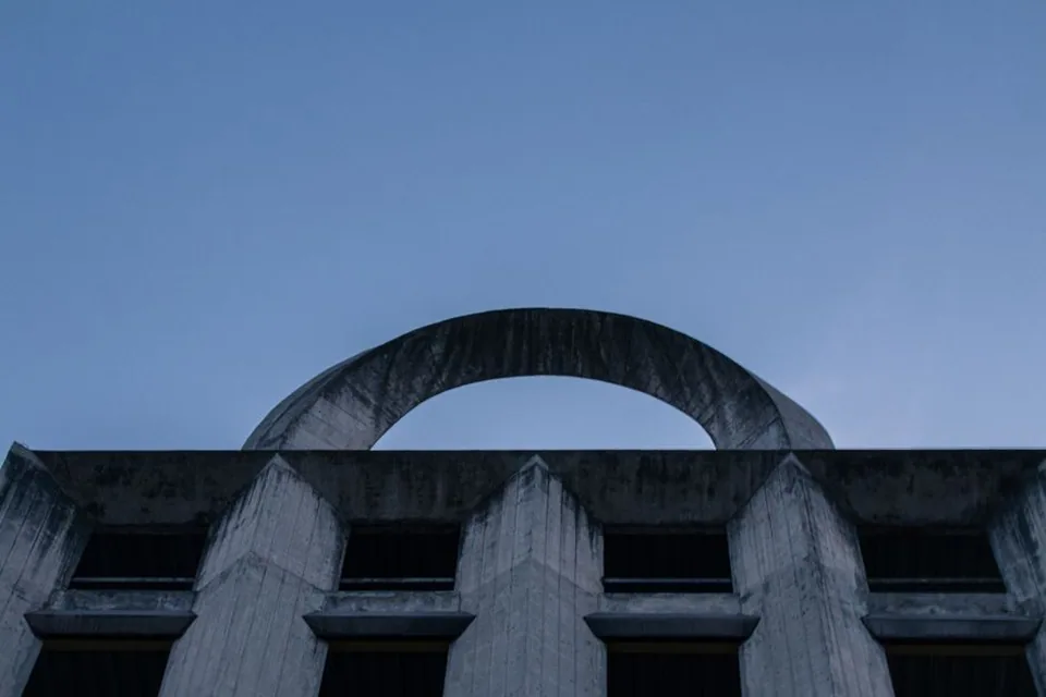 Arco de concreto de arquitetura modernista recortado contra o céu azul