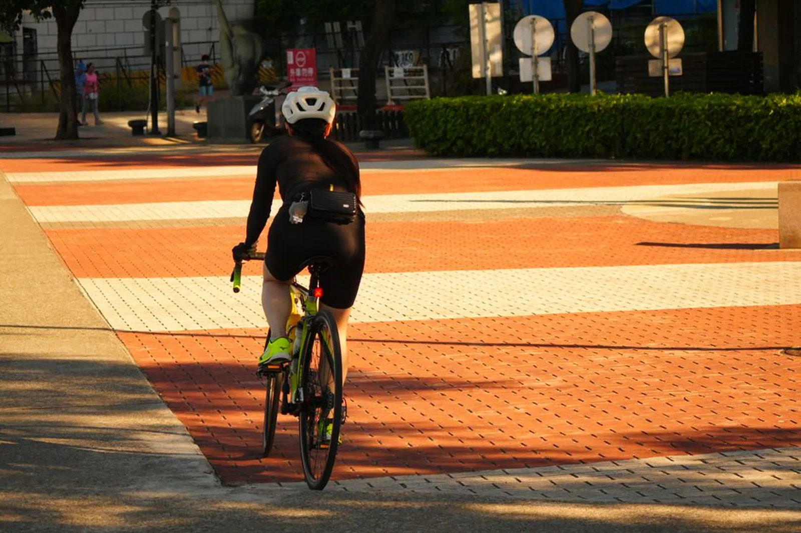 Ciclista pedalando em faixa de ciclovia alaranjada na cidade