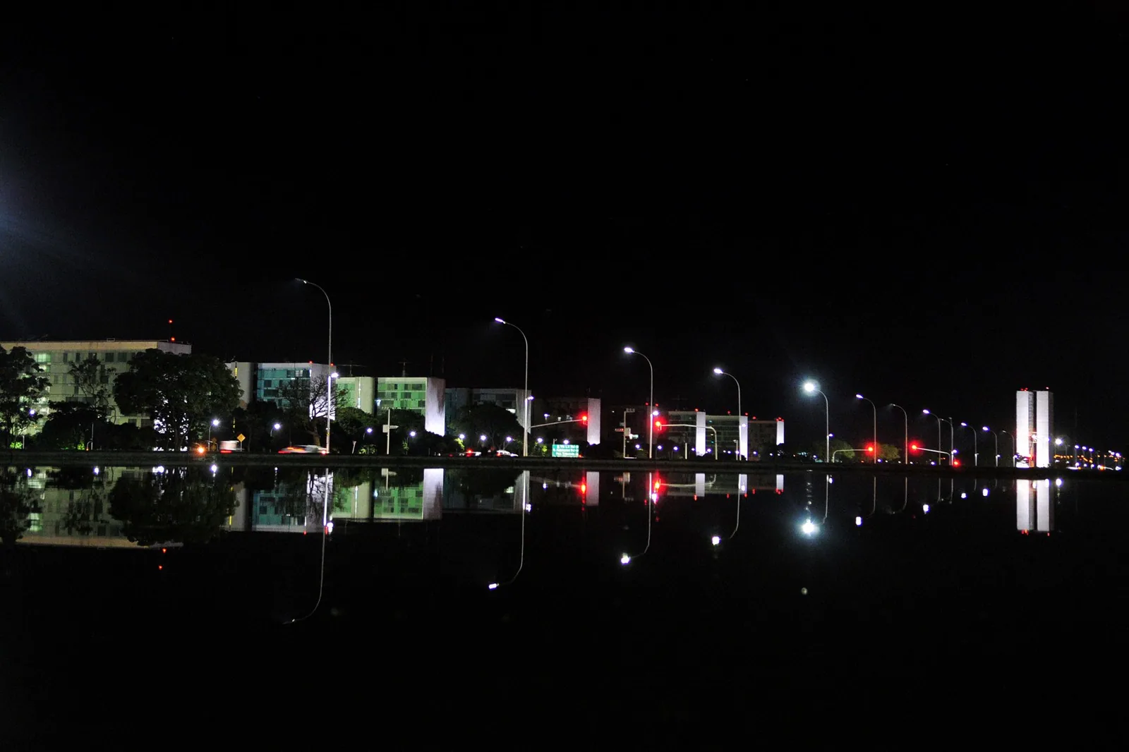Esplanada dos Ministérios à noite, com os prédios iluminados refletidos no espelho d'água