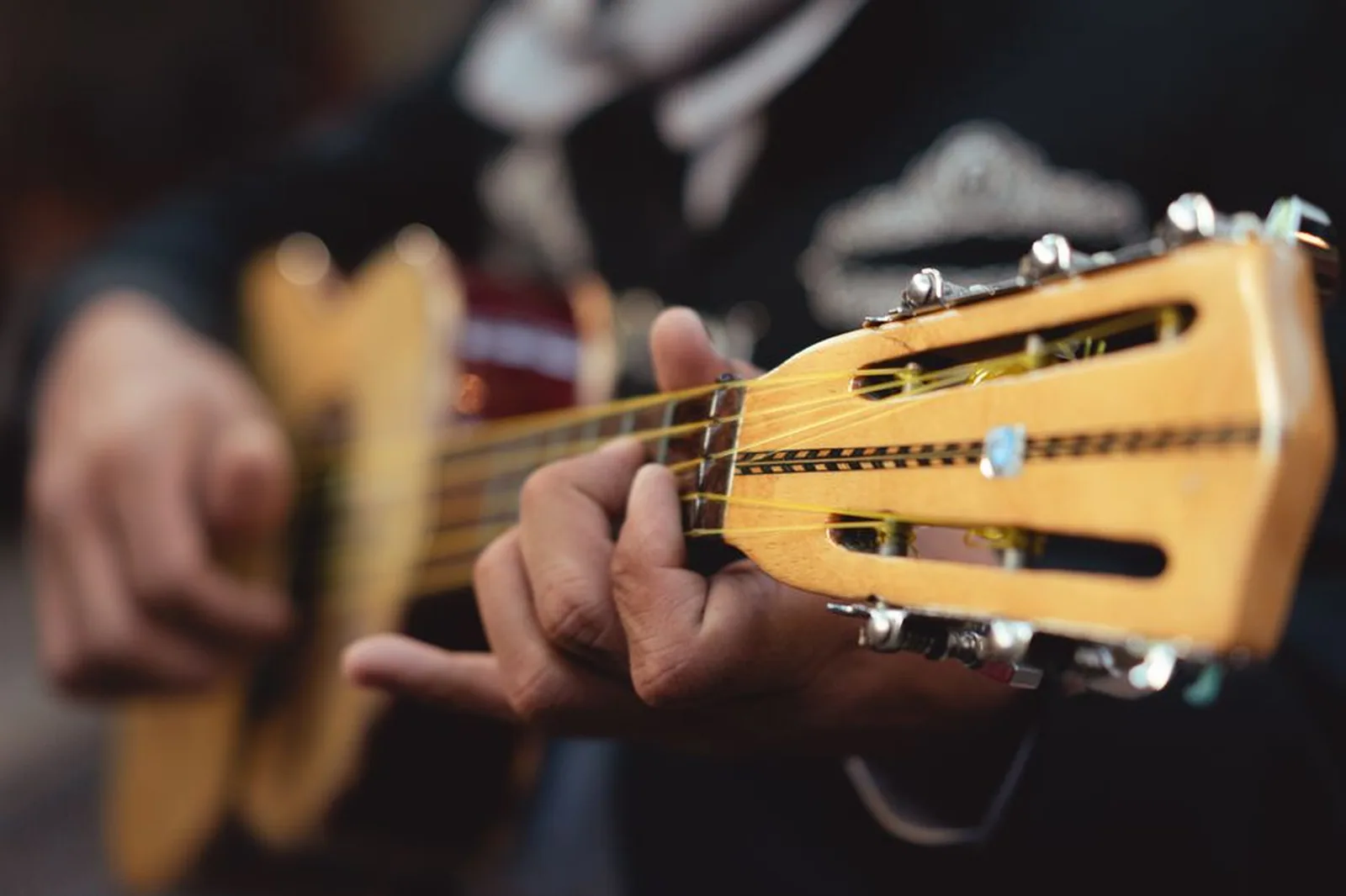 Mãos tocando cavaquinho em close, com foco nas cordas