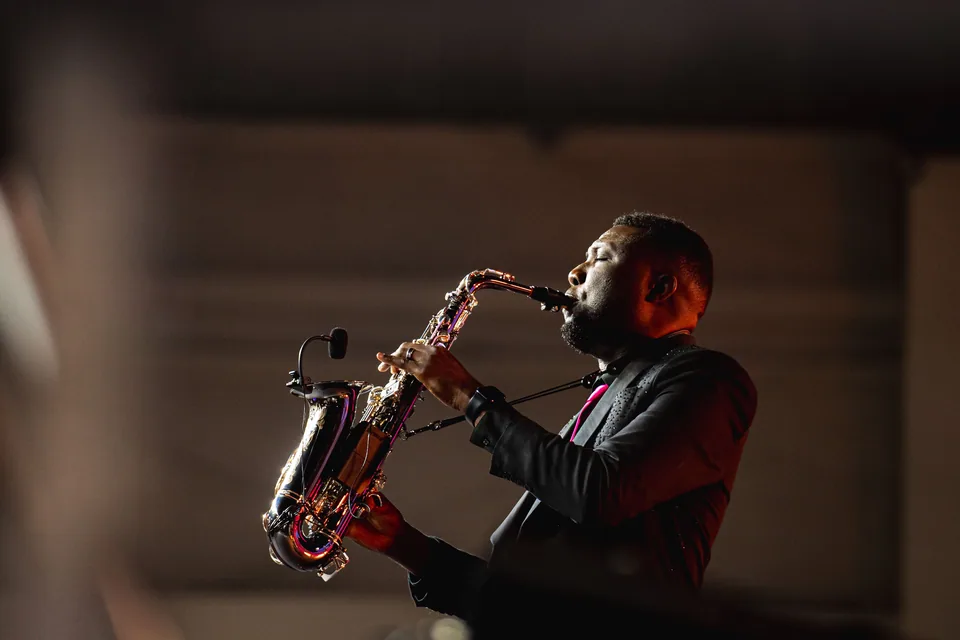 Saxofonista toca em palco com luz baixa durante show de jazz