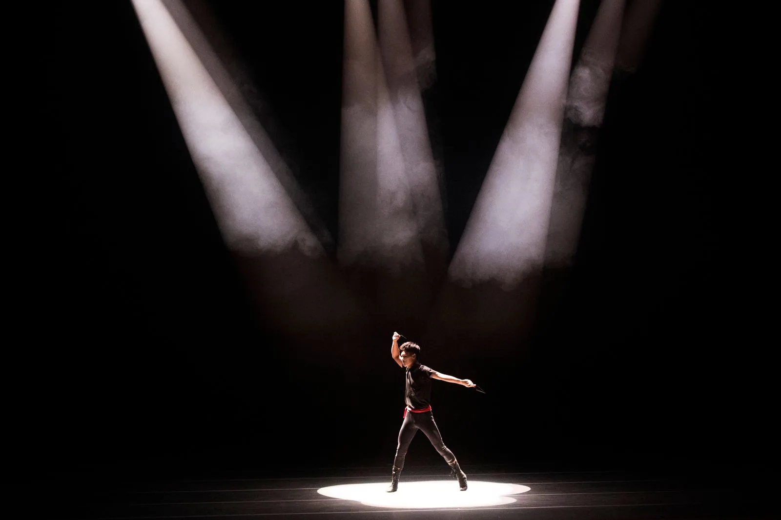 Artista sozinho sob feixes de holofotes em palco escuro, em foto de banco de imagens que ilustra o teatro visual