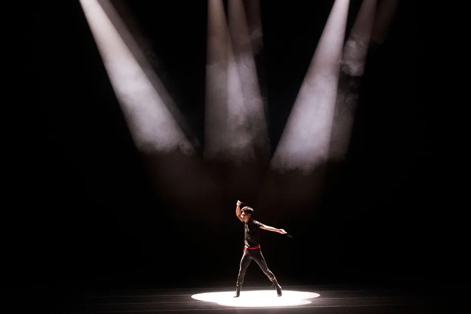 Artista sozinho sob feixes de holofotes em palco escuro, em foto de banco de imagens que ilustra o teatro visual
