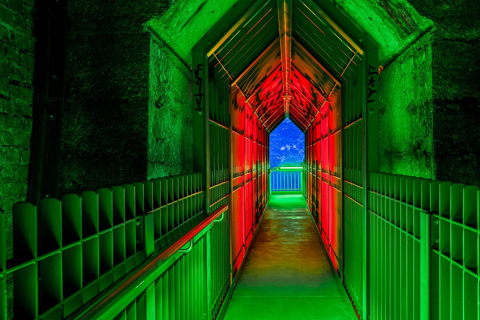 Corredor industrial iluminado por luzes verdes e vermelhas, imagem ilustrativa