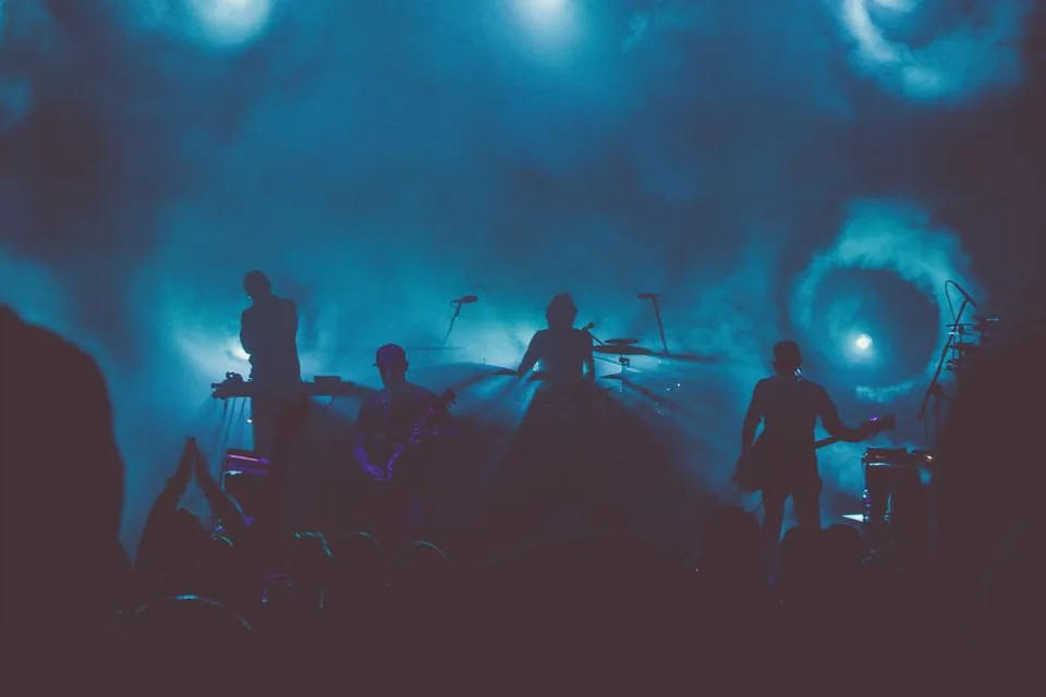 Banda em silhueta no palco, com luz azul e fumaça; foto ilustrativa, não é do show