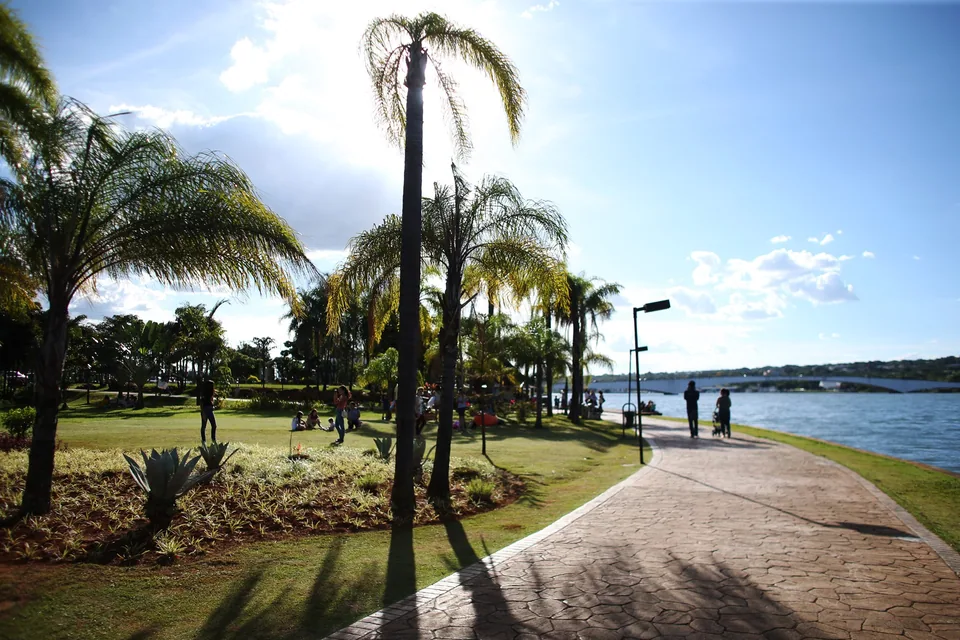 Calçadão com palmeiras e gramado na orla do Pontão do Lago Sul, com o lago Paranoá e a Ponte JK ao fundo, em foto de arquivo