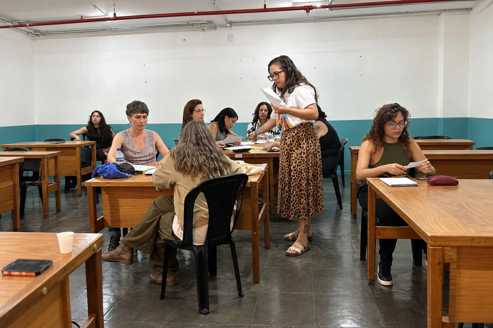 Participantes sentados em mesas de madeira durante aula de capacitação no EIXO, no Setor Comercial Sul
