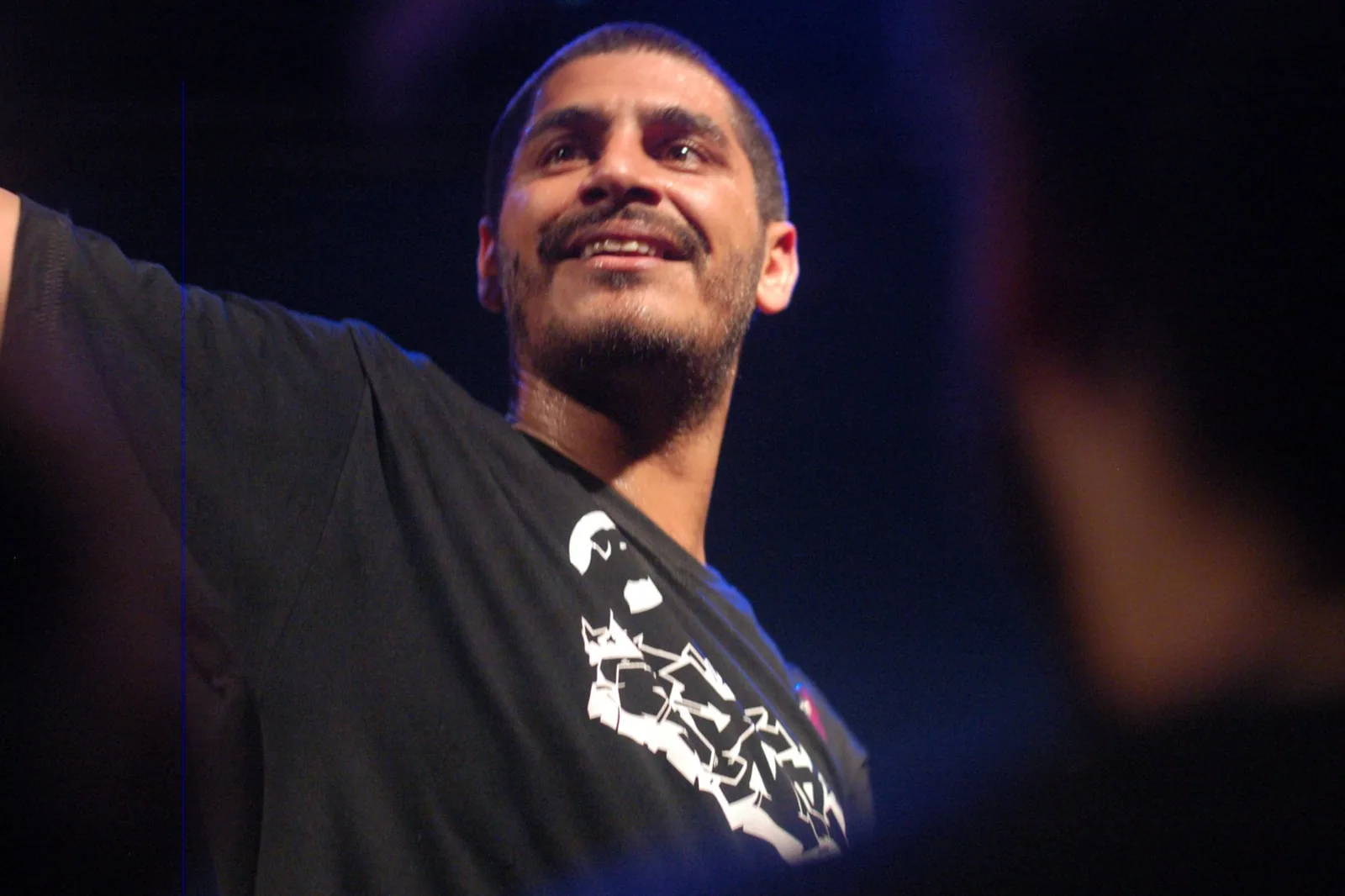 Criolo sorrindo no palco, de braço aberto, em foto de arquivo