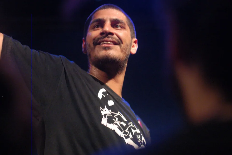 Criolo sorrindo no palco, de braço aberto, em foto de arquivo