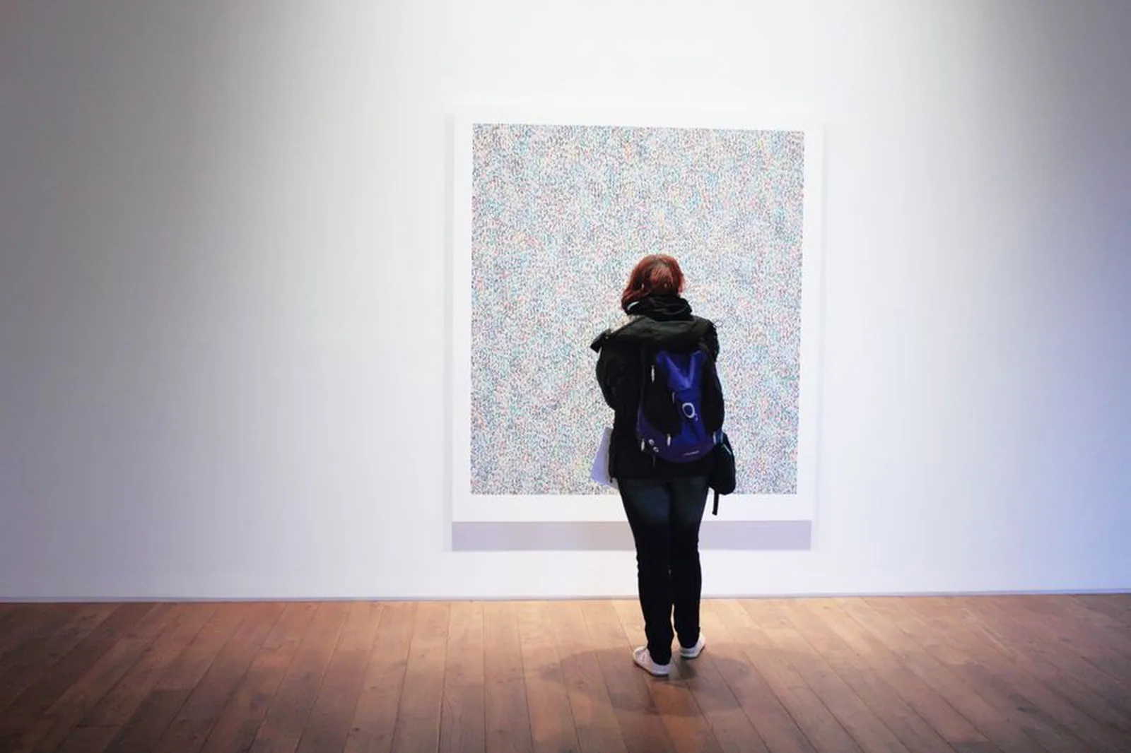 Visitantes caminhando por um grande salão de exposição de arte