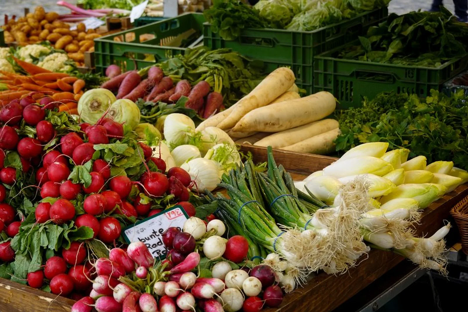 Banca de feira com verduras e legumes frescos organizados em caixas