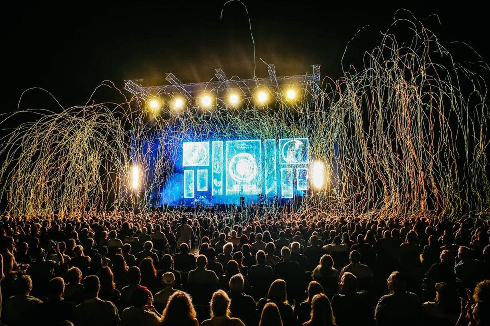Público de festival ao ar livre diante de palco iluminado