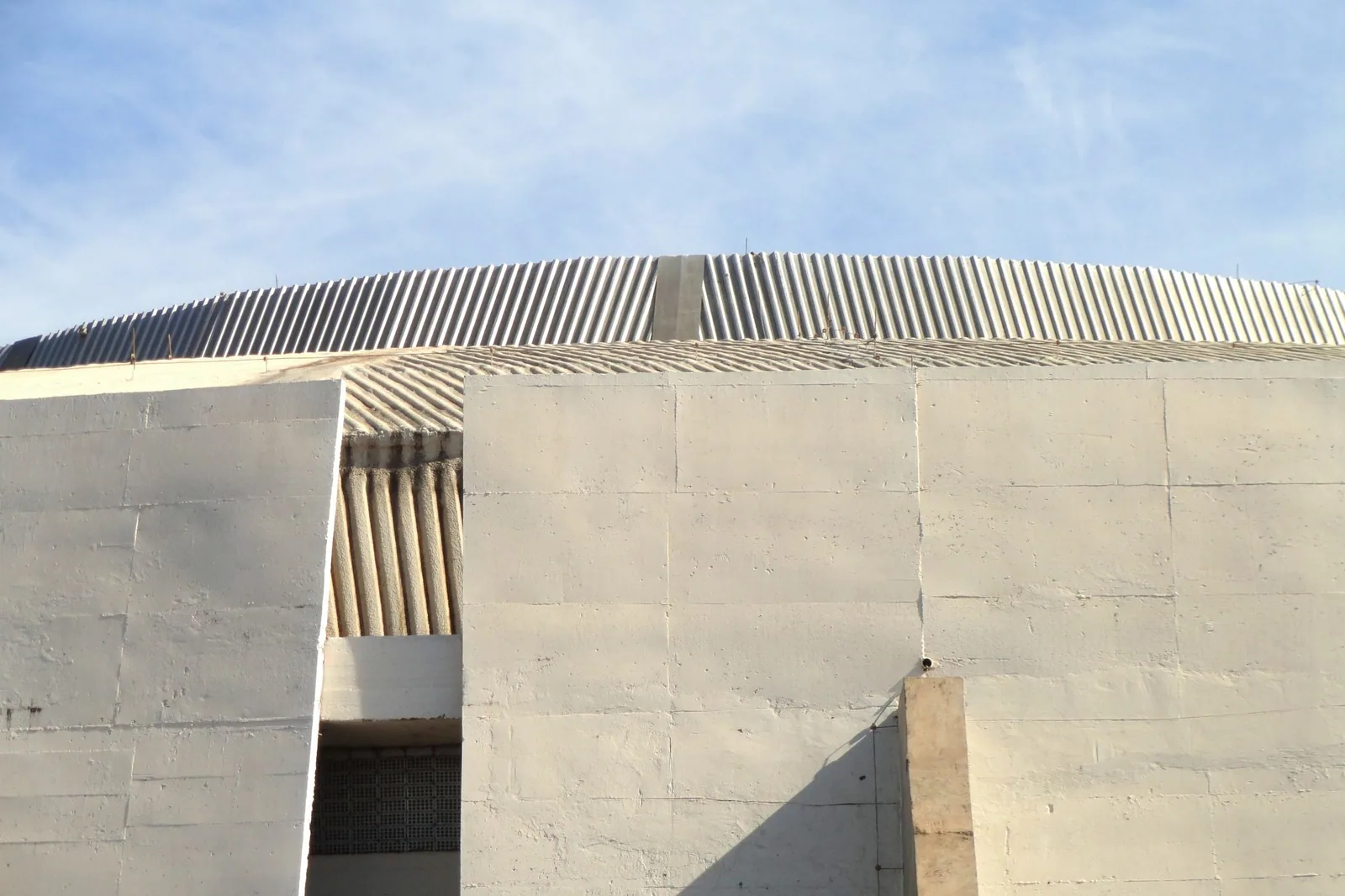 Parede de concreto e cobertura com nervuras do Ginásio Nilson Nelson, em Brasília, sob céu azul