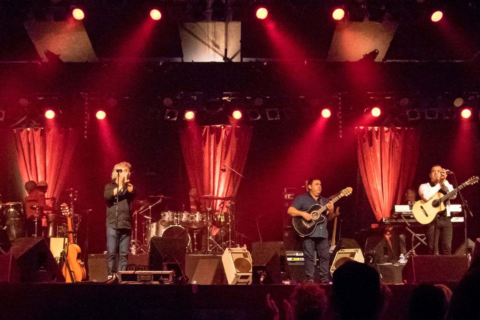Integrantes do Gipsy Kings em palco com cortinas e luzes vermelhas, em show de 2016 na Alemanha