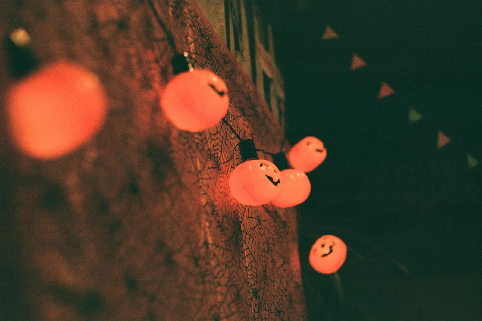 Cordão de luzes em formato de abóbora de Halloween aceso numa parede escura, em clima de festa