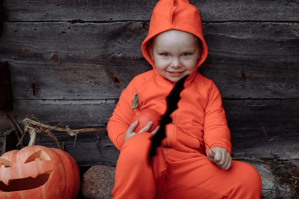 Criança fantasiada de Halloween com fantasia laranja e abóbora decorada