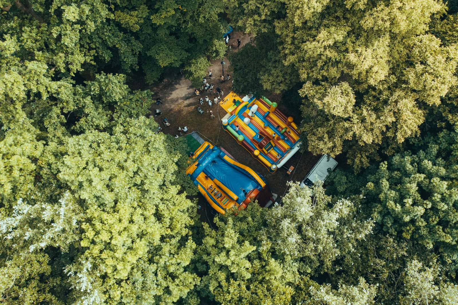 Vista aérea de dois brinquedos infláveis coloridos montados em uma clareira cercada de árvores
