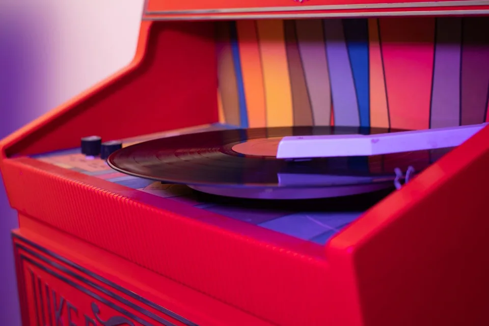 Vitrola de uma jukebox vermelha com um disco de vinil girando e luz roxa ao fundo
