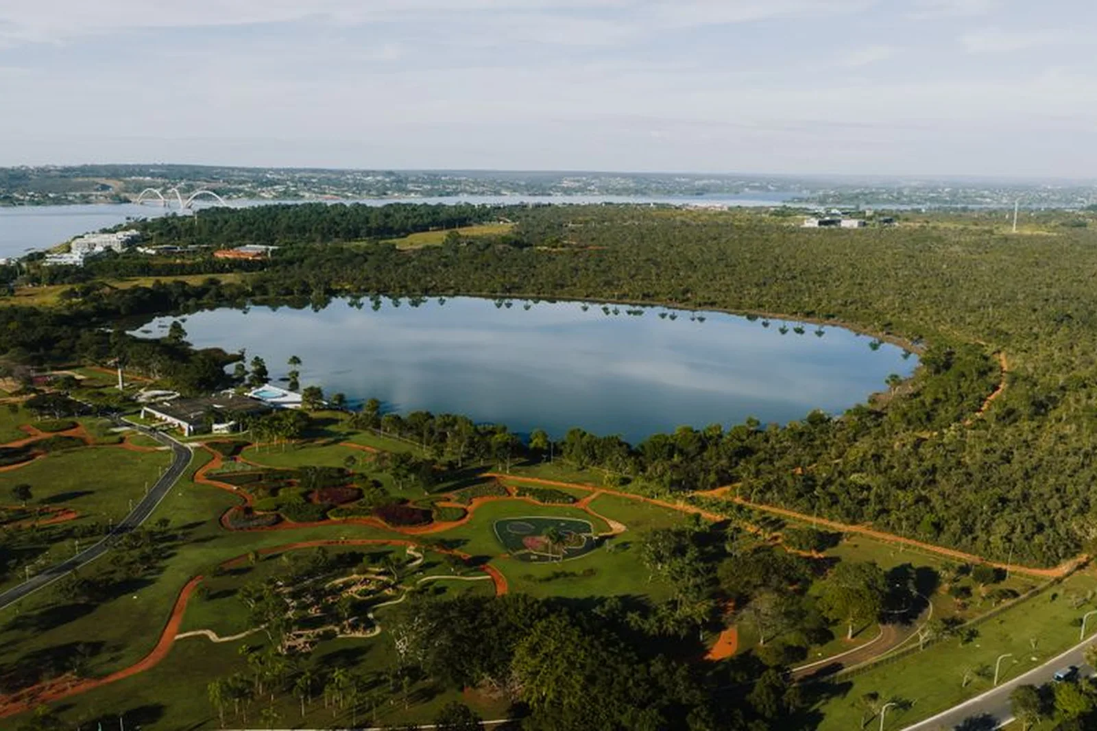 Vista aérea de Brasília com lago, área verde e a Ponte JK ao fundo
