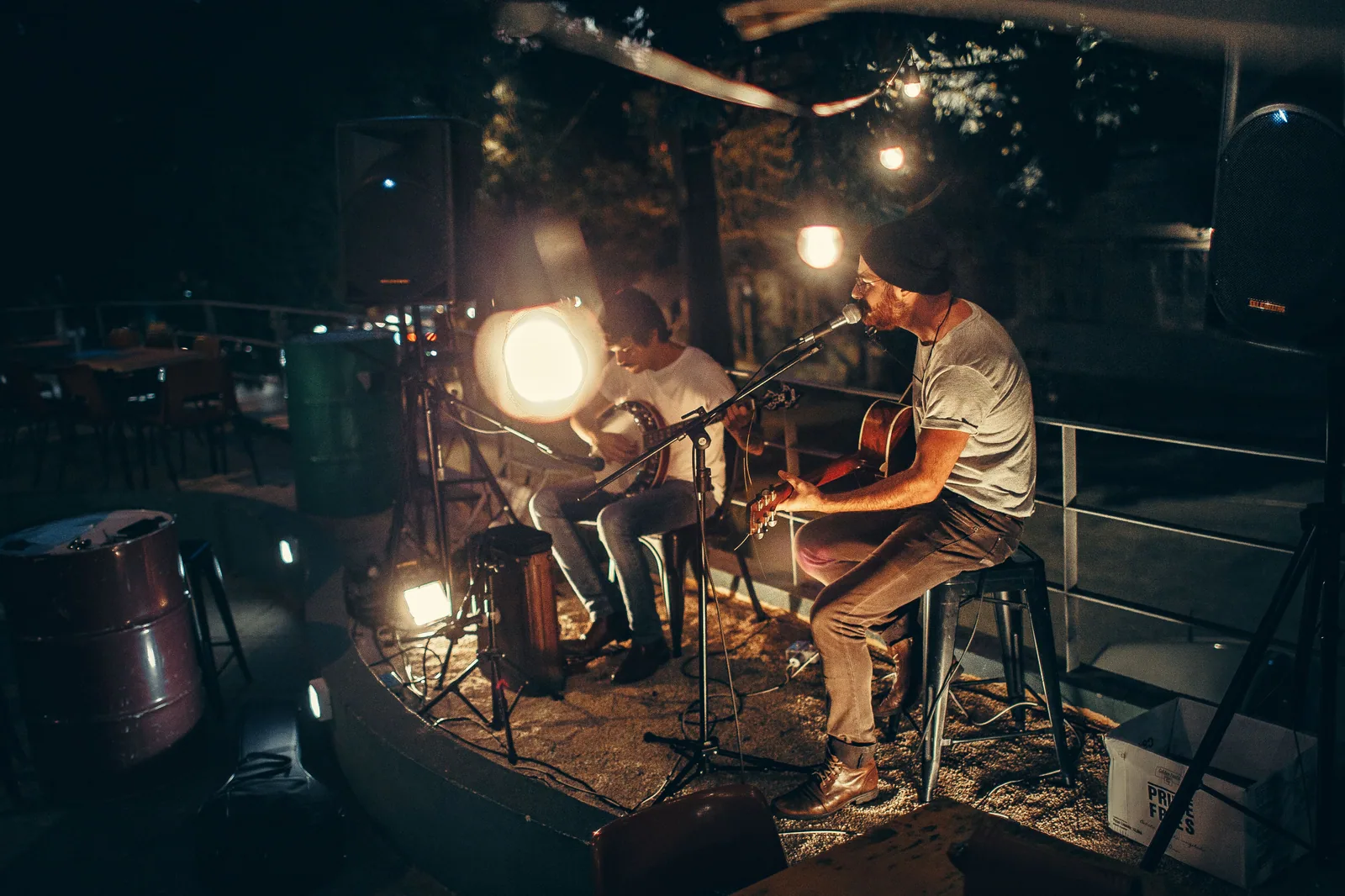 Dois músicos tocam violão ao ar livre à noite, foto ilustrativa