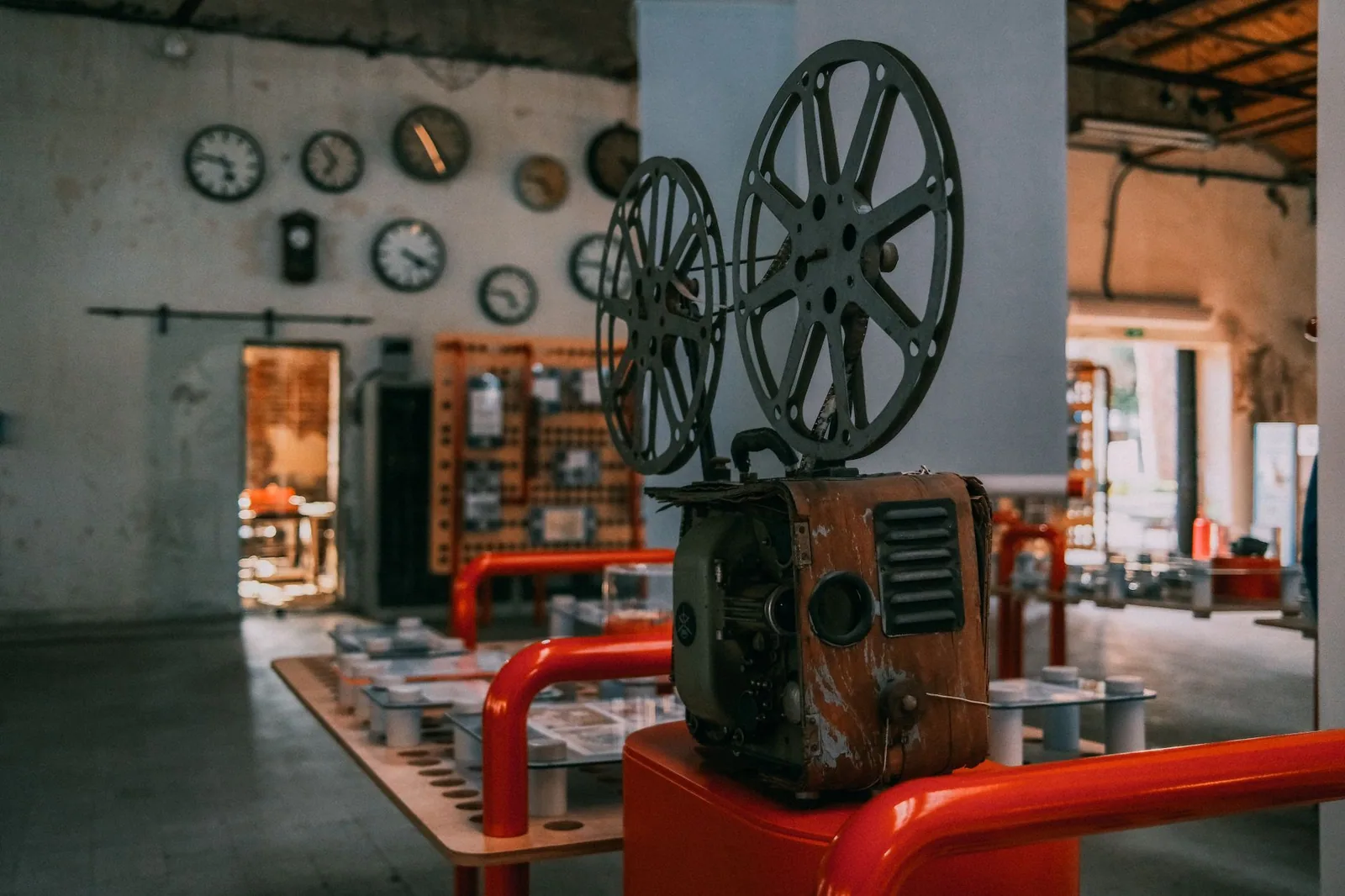 Projetor de filmes antigo, com duas bobinas, em um espaço de exposição; imagem ilustrativa, não é do espetáculo