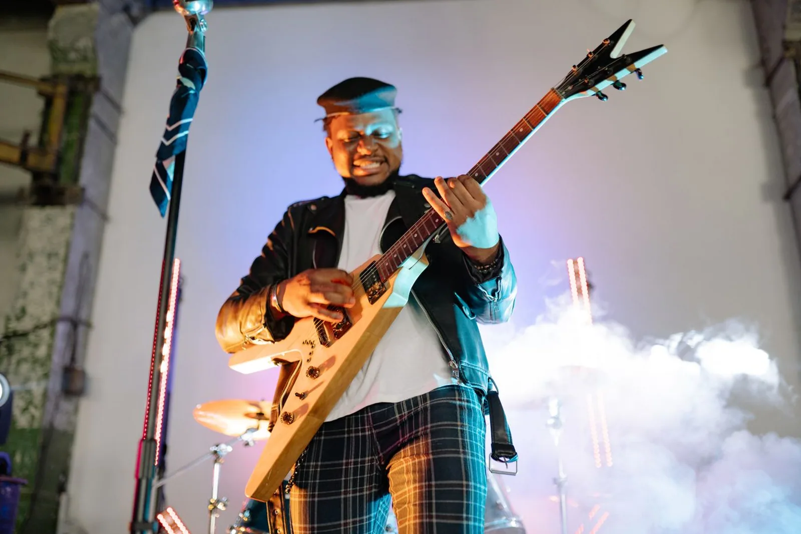 Guitarrista com guitarra em V se inclina para a frente em palco com fumaça