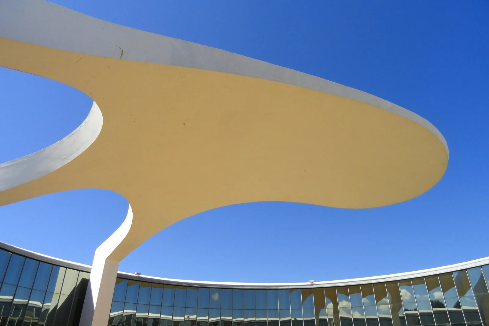 Cobertura em curva do Memorial dos Povos Indígenas, em Brasília, vista de baixo contra o céu azul