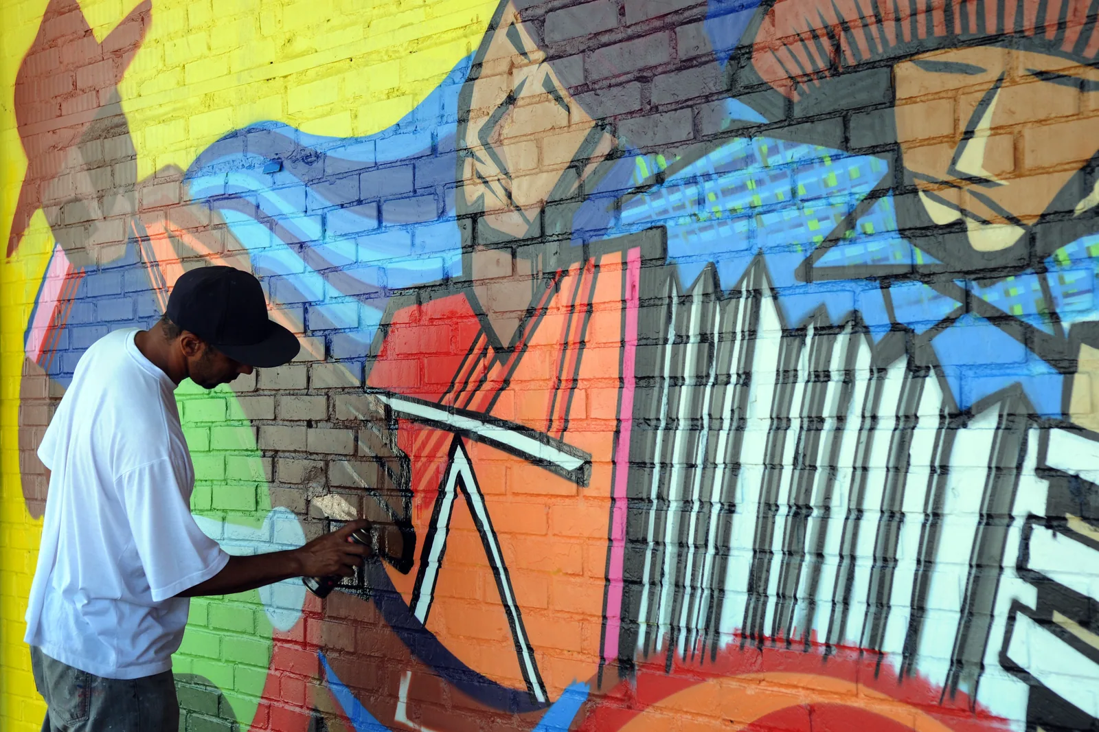 Artista grafita um mural colorido em parede de tijolos na área central de Ceilândia, em foto de arquivo