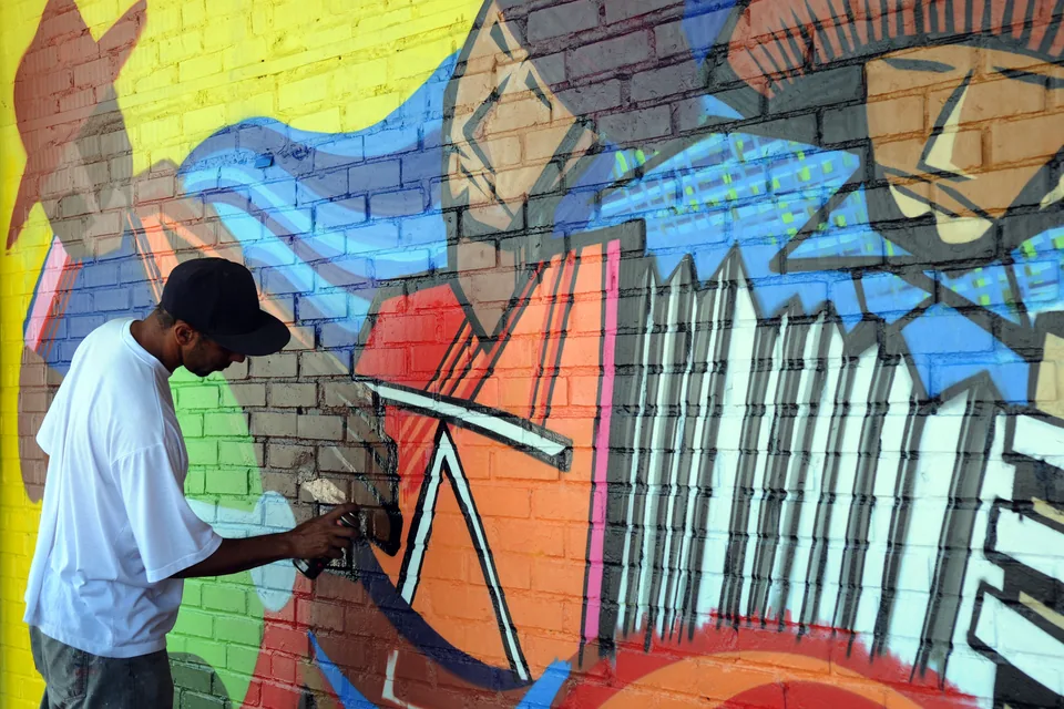 Artista grafita um mural colorido em parede de tijolos na área central de Ceilândia, em foto de arquivo