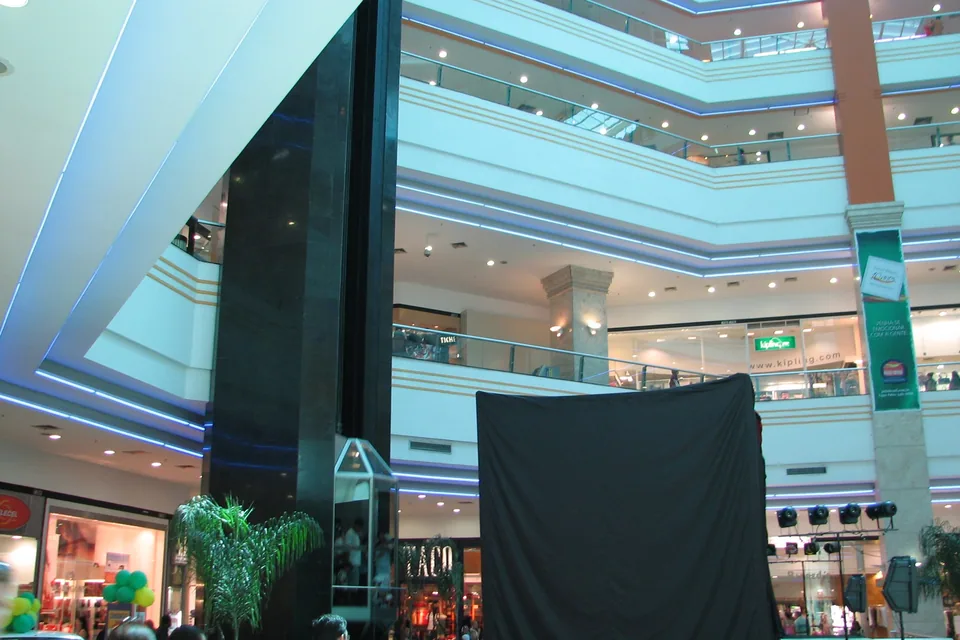 Átrio do Pátio Brasil Shopping com vários andares de lojas, palco montado e luzes azuis nas bordas dos corredores
