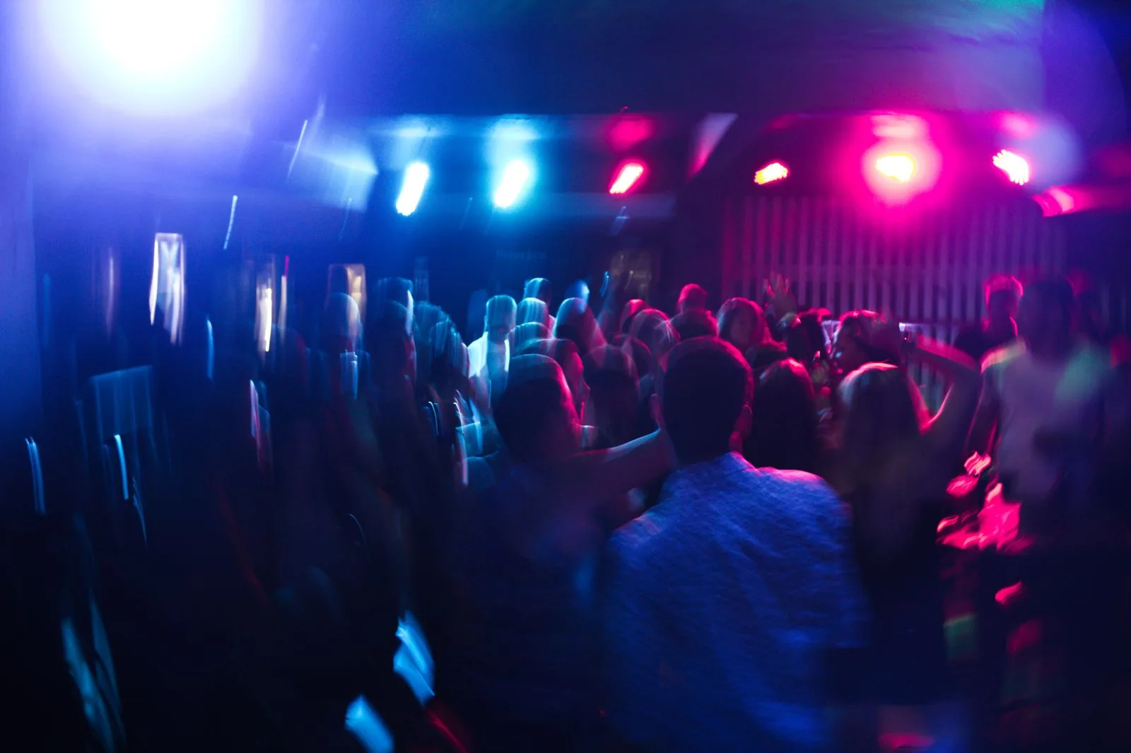 Pista de dança de balada com luzes azuis e rosa e pessoas dançando em movimento (foto ilustrativa)