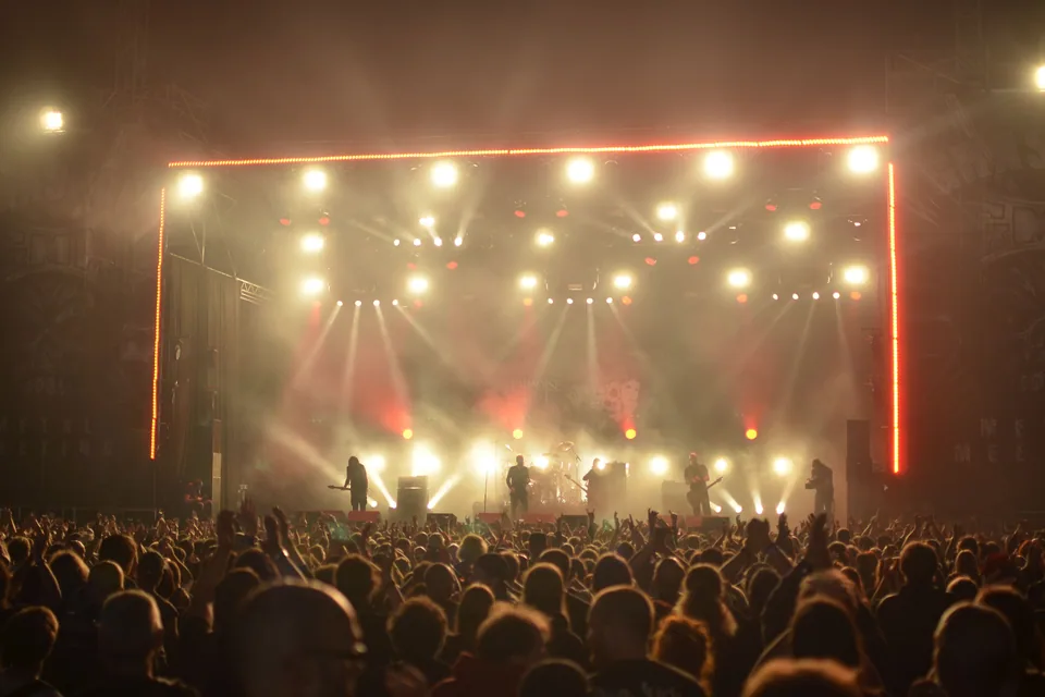 Palco com refletores e público de costas em show de rock, foto ilustrativa