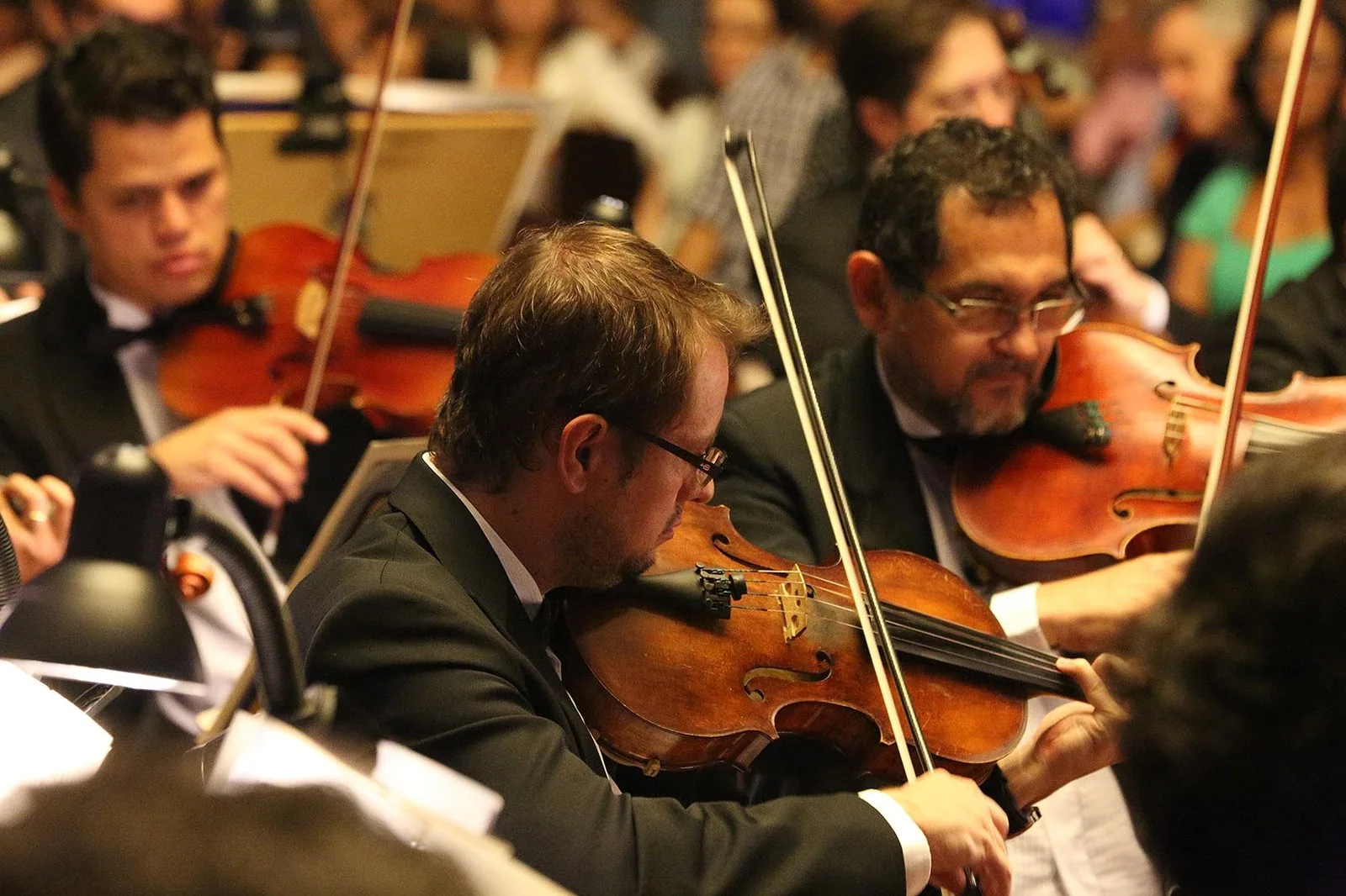 Violinistas da Orquestra Sinfônica do Teatro Nacional tocando em concerto, em foto de 2015