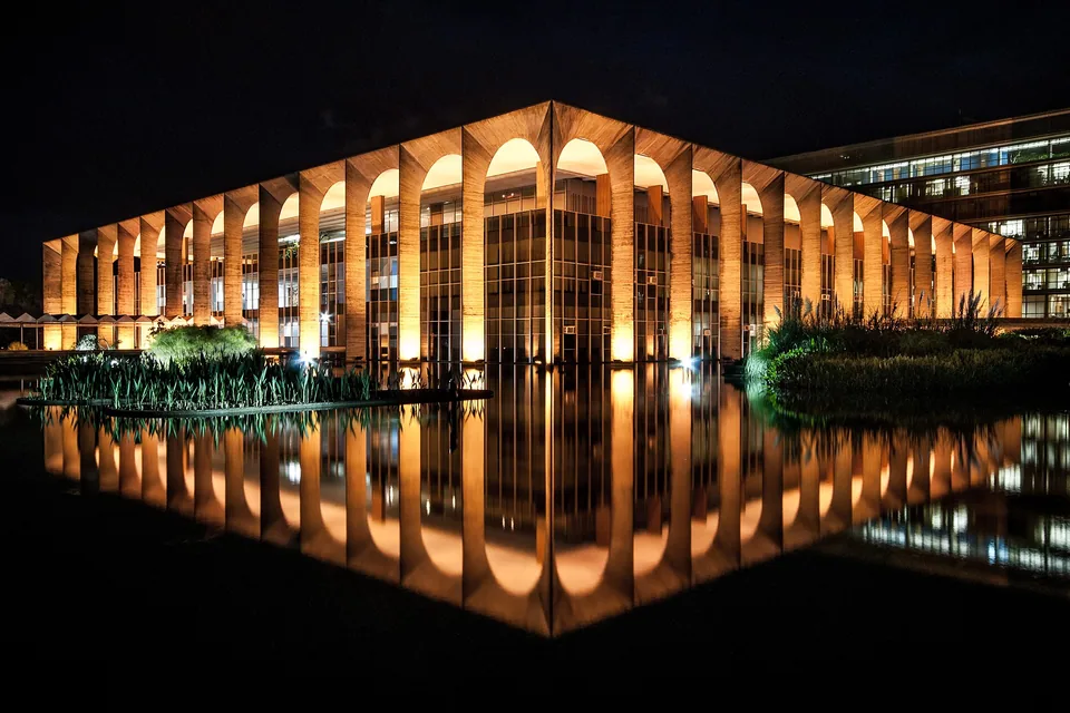Palácio Itamaraty à noite, com o reflexo no espelho d'água. Foto: Dlaurini, CC BY-SA 4.0, via Wikimedia Commons.