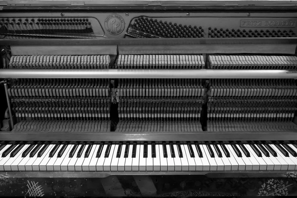 Piano aberto em preto e branco mostrando o teclado e o mecanismo de martelos