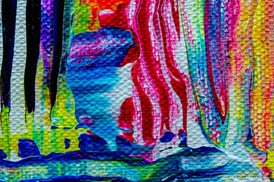 Close de tela pintada com faixas verticais de tinta azul, rosa, amarela e preta