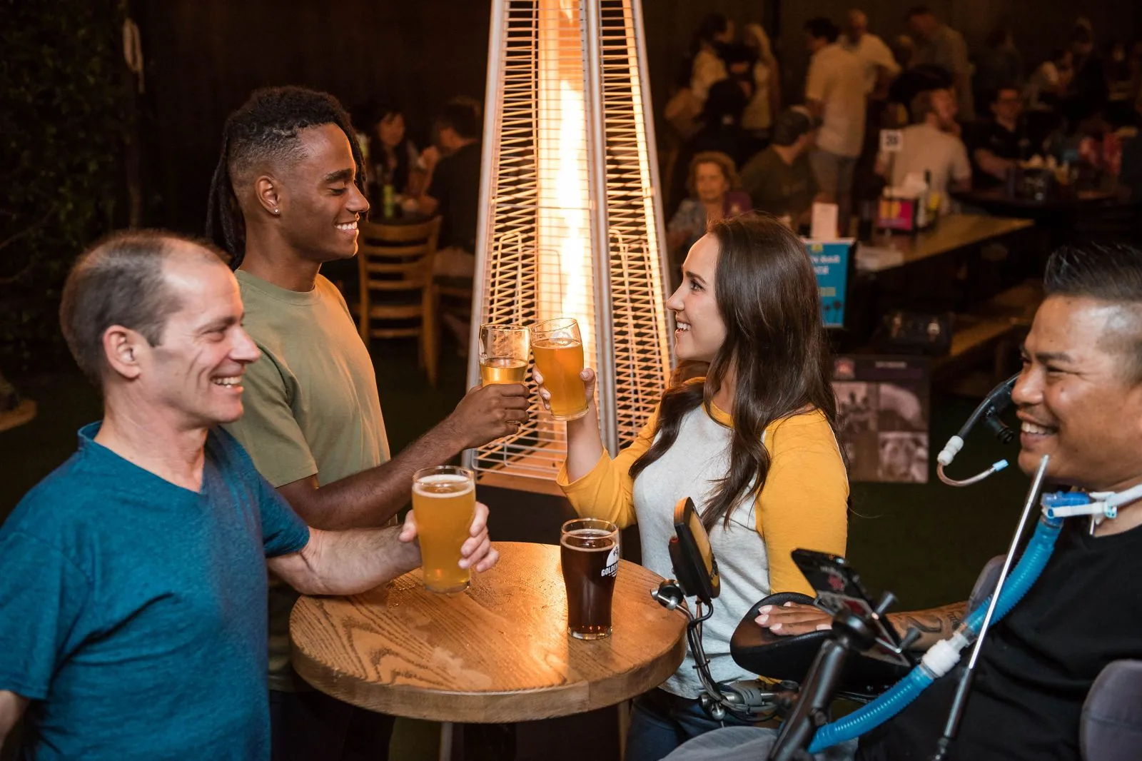 Grupo de amigos brindando com copos de cerveja em uma mesa alta de bar (foto de arquivo)
