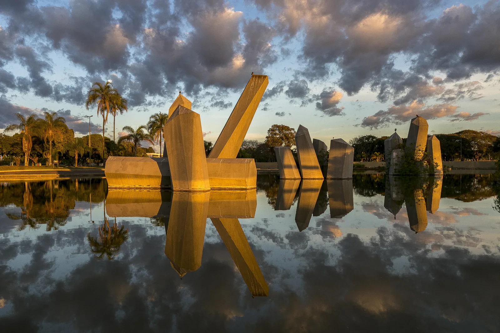 Praça dos Cristais ao amanhecer, com os blocos de concreto e o espelho d'água refletindo o céu, no Setor Militar Urbano de Brasília