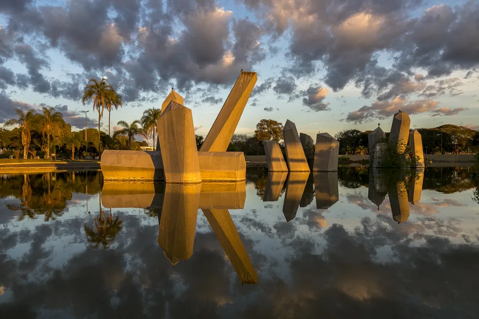 Praça dos Cristais ao amanhecer, com os blocos de concreto e o espelho d'água refletindo o céu, no Setor Militar Urbano de Brasília