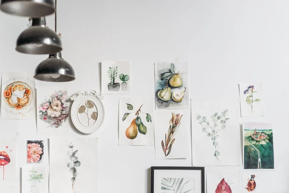 Aquarelas de plantas e frutas coladas numa parede branca, em foto ilustrativa sem relação com a mostra