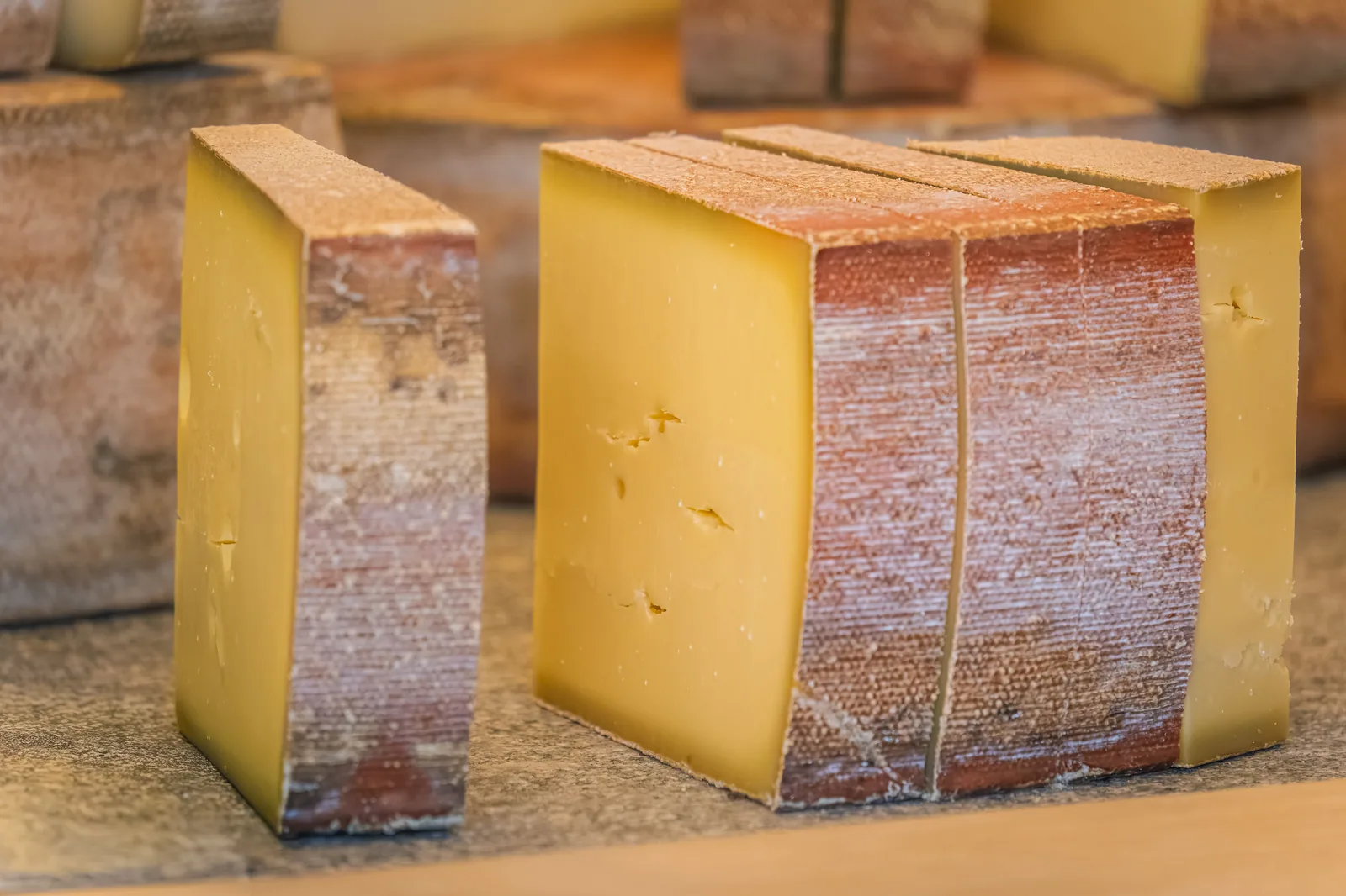 Peças de queijo artesanal de casca natural cortadas e expostas sobre bancada de madeira