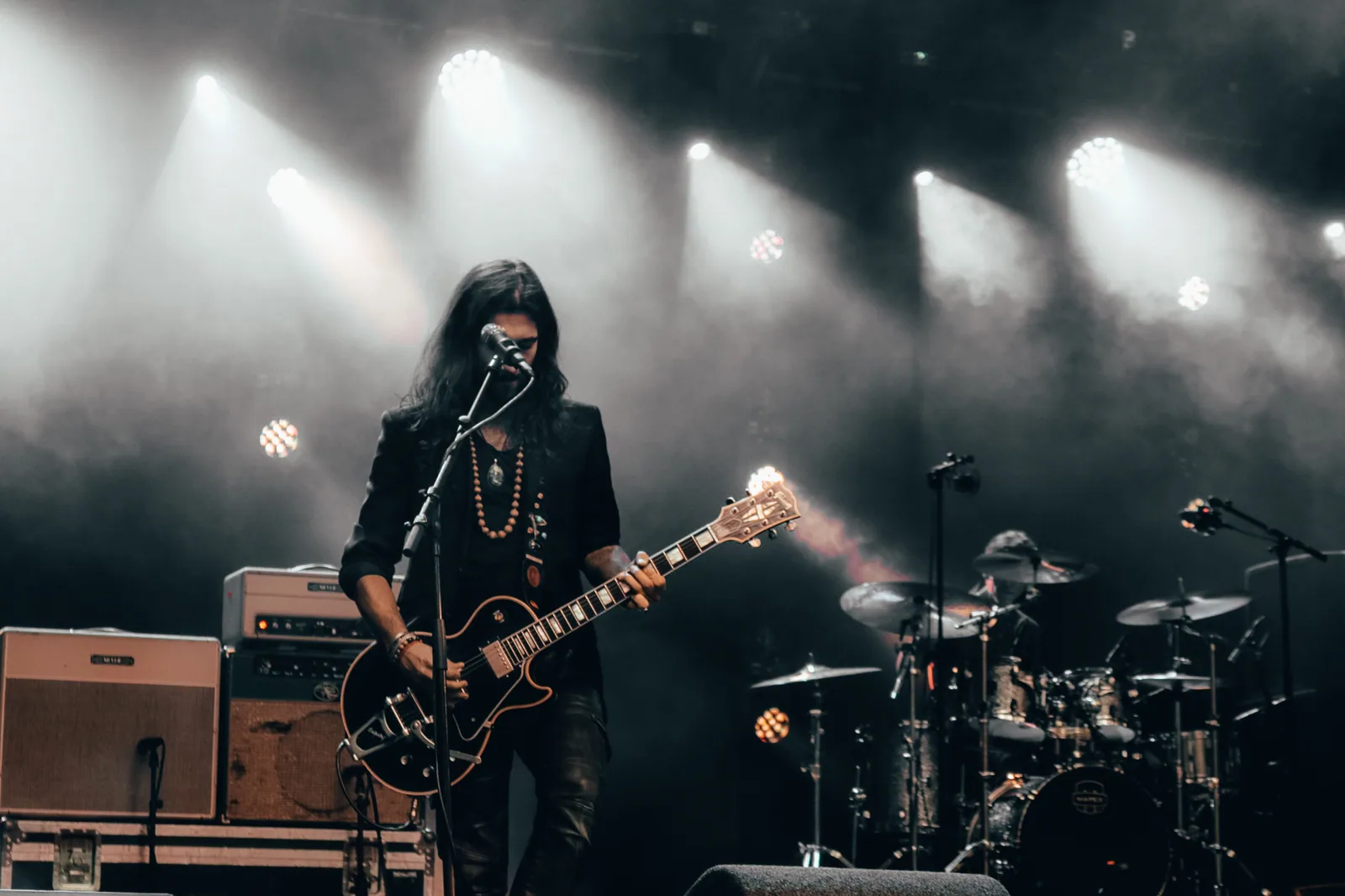 Guitarrista e baterista tocam em palco com fumaça, foto ilustrativa