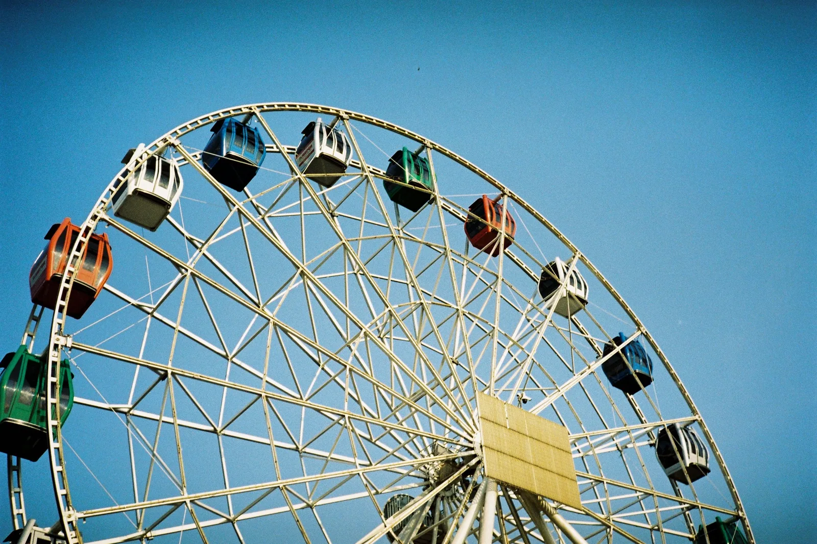 Roda-gigante com cabines coloridas contra um céu azul