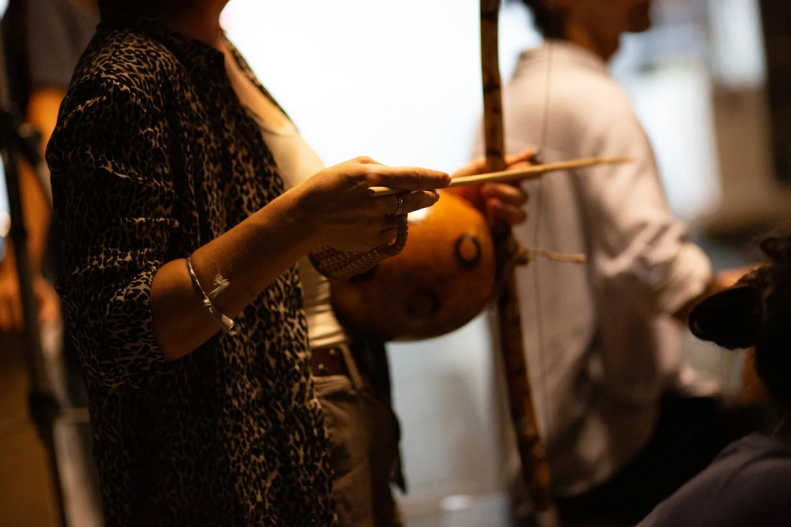 Mãos de músico com a baqueta junto ao berimbau durante roda de capoeira