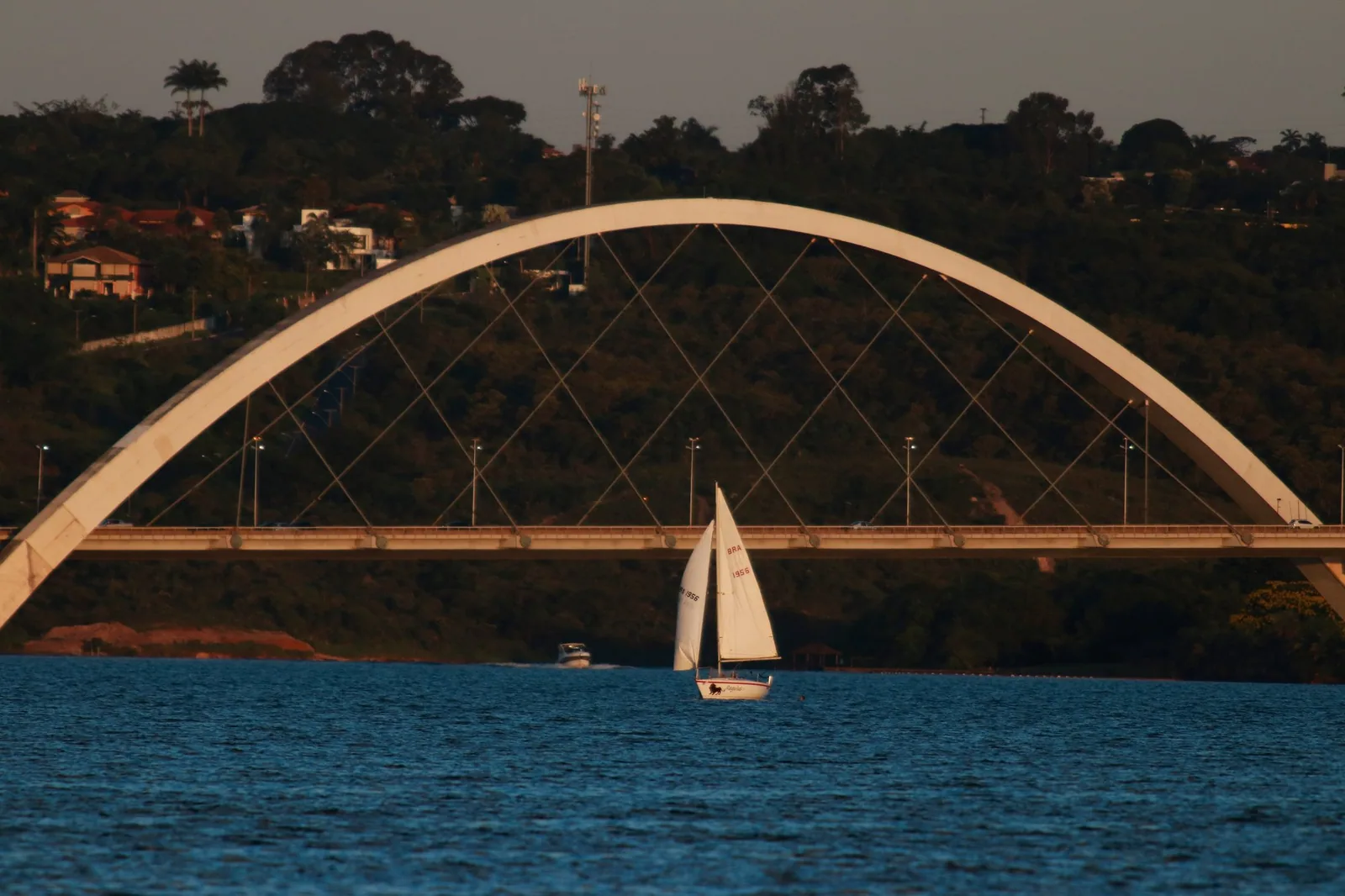 Veleiro no Lago Paranoá diante do arco da Ponte JK ao entardecer
