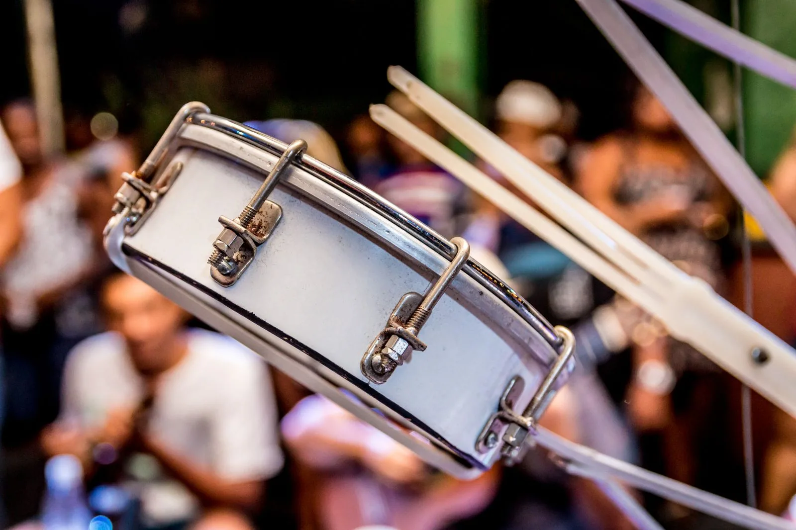 Close de um tamborim com a roda de samba desfocada ao fundo