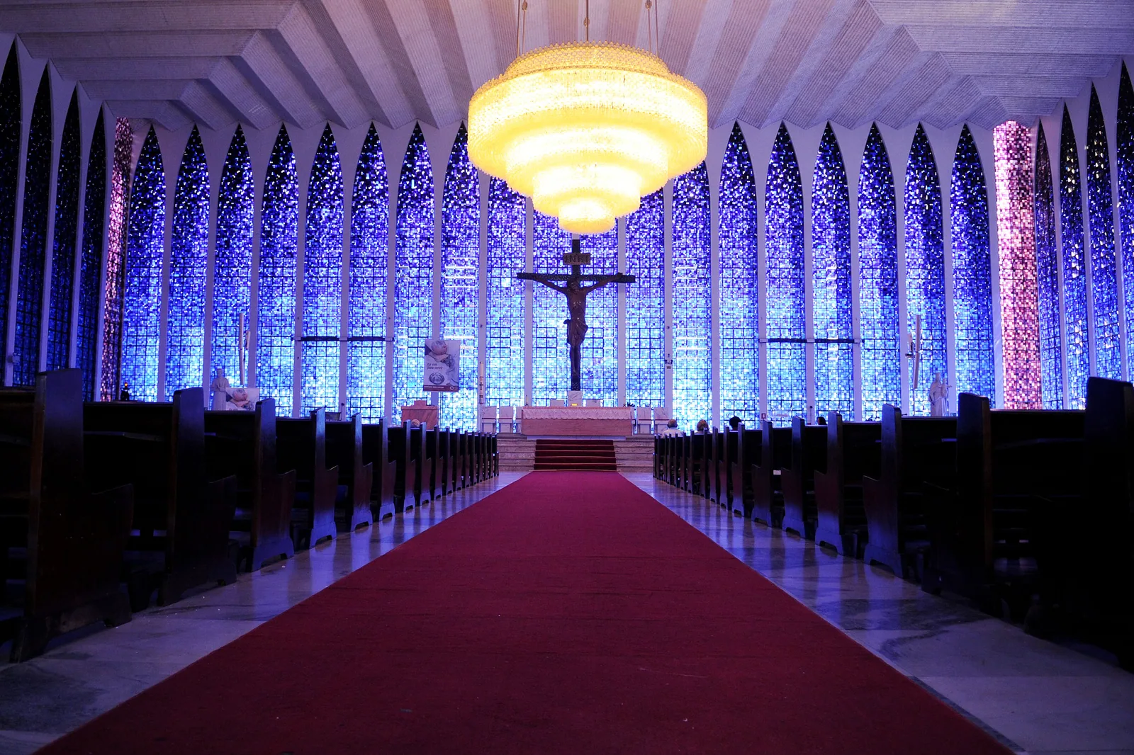 Interior do Santuário Dom Bosco em Brasília, com os vitrais em doze tons de azul e o lustre de vidro de Murano sobre o corredor central