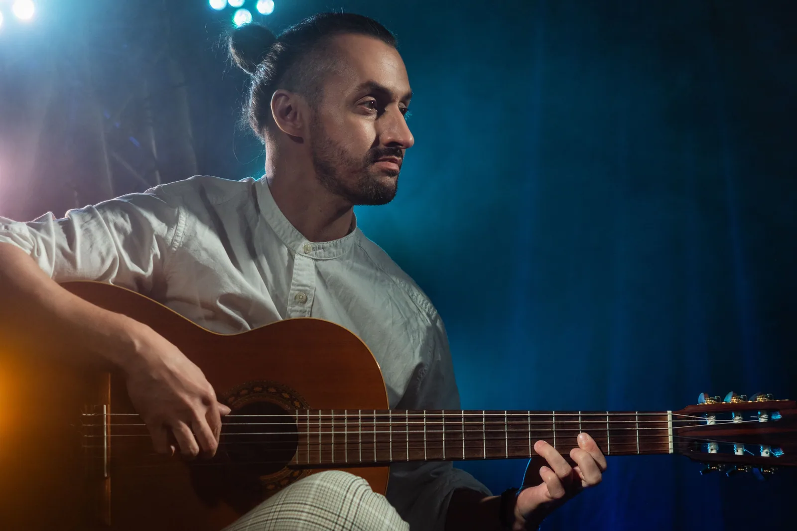 Músico tocando violão em palco com iluminação azul