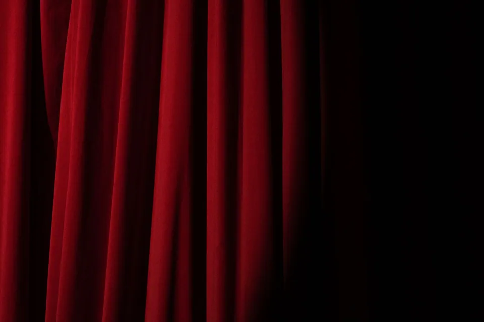 Detalhe de cortina de veludo vermelho de teatro com sombra à direita